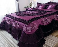 a bed with purple and black bedspreads on it