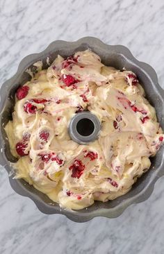 a cake pan filled with frosting and strawberries on top of a marble counter