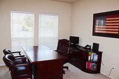 an office with two chairs and a desk in front of the window is decorated with american flag