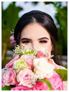 a woman holding a bouquet of pink and white flowers in front of her face with green leaves