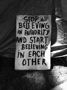 a sign that reads stop believing in authority and start believing in each other