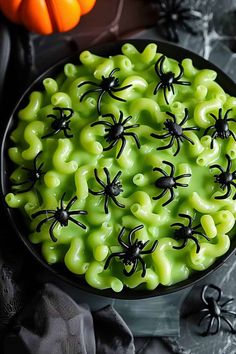 a bowl filled with green jello covered in black spider webs and orange pumpkins