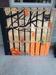 a wooden pallet with an orange pumpkin painted on it, sitting in front of a door