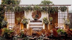 an outdoor area with potted plants and wooden benches in front of a white wall