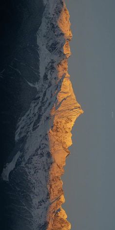 the top of a mountain with snow on it's sides and light coming from below