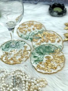 three glass coasters with gold and green designs on them next to pearls, beads and other items