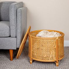 a grey couch sitting next to a wooden table on top of a carpeted floor