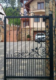 a car is parked in front of a house behind a wrought iron gate that leads to the driveway