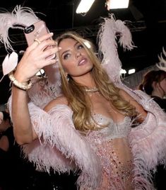 a woman taking a selfie with her cell phone in front of other people at a party