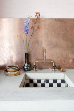 a kitchen sink sitting under a faucet next to a vase filled with flowers