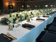 a long table is set up with black and gold place settings