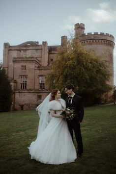 a bride and groom standing in front of a castle