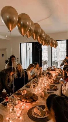 a group of people sitting around a long table with plates and candles in front of them