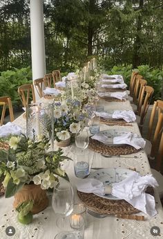 a long table is set with white linens and place settings for the dinner guests