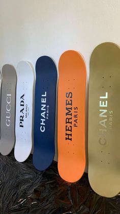 five skateboards are lined up in a row against a white wall with the name chanel printed on them