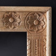 an ornate wooden frame with carved flowers and leaves on the edge, against a black background