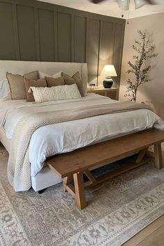 a bedroom with a large bed and wooden bench in the middle, along with two lamps on either side of the bed