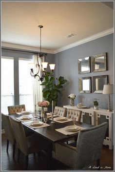 a dinning room table and chairs in front of a chandelier with mirrors on the wall