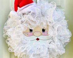 a christmas wreath with a santa claus face on the front door and white mesh netting around it