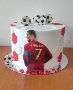 there is a cake with a soccer player on it and two balls in the background