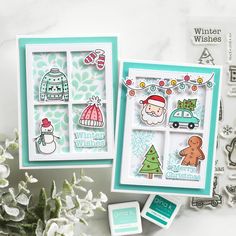 two cards with christmas scenes on them next to some snowflakes and white flowers