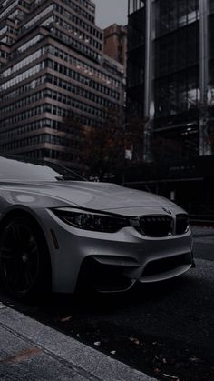 a white car is parked on the side of the road in front of tall buildings