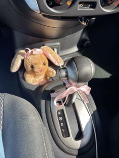 a stuffed animal in the center console of a car with a pink ribbon on it