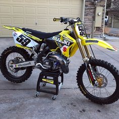 a yellow dirt bike parked in front of a garage