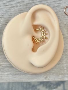 a pair of gold colored earring sitting on top of a wooden table