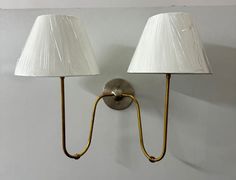 two lamps are on the wall next to each other, one has a white shade