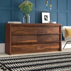 a room with blue walls and a black and white rug on the floor next to a wooden dresser