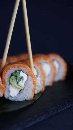 sushi rolls on a plate with chopsticks sticking out of the top one