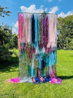 an art installation made out of plastic beads and streamers on the ground in a park