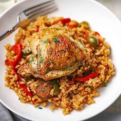 a white plate topped with rice and chicken next to a fork on a tablecloth