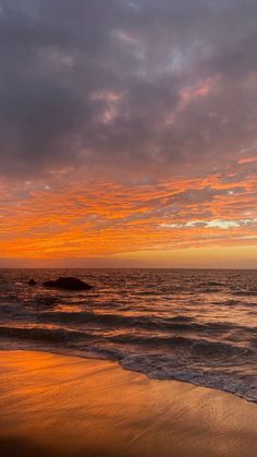 an orange and pink sunset over the ocean with waves crashing on it's shore