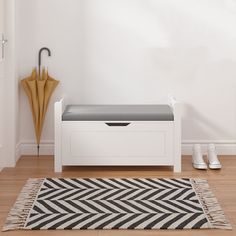 a white bench sitting on top of a hard wood floor next to a wall with an umbrella