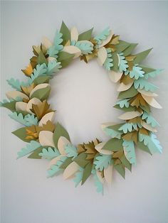 a wreath made out of paper with leaves on the front and sides, hanging on a wall