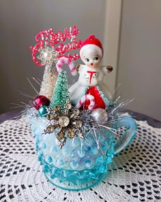 a glass bowl with some ornaments in it on top of a doily covered table