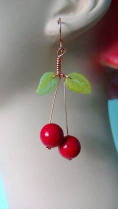 two cherries are hanging from a wire on a mannequin's head