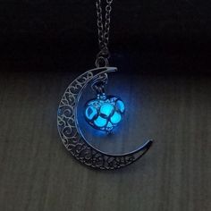 a glowing crescent moon and paw prints glow in the night sky as it hangs from a chain