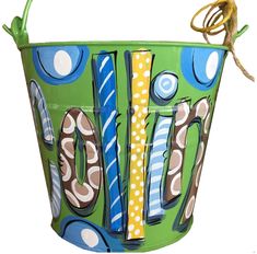 a green bucket with the word joy painted on it and a rope hanging from the handle