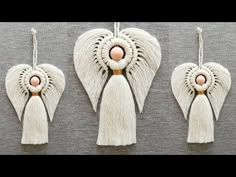 three white angel wings with pink beads and tassels hanging from the side on a gray background