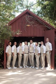 a group of men standing next to each other in front of a barn