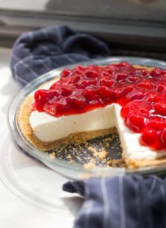 a cheesecake topped with cherries on top of a glass plate