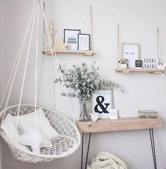 a white hammock hanging from a wall next to a wooden table and shelf