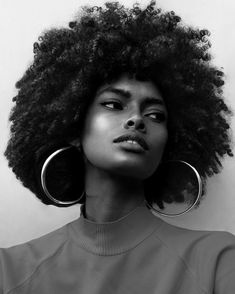 a black and white photo of a woman with large hoop earrings on her head, looking off to the side