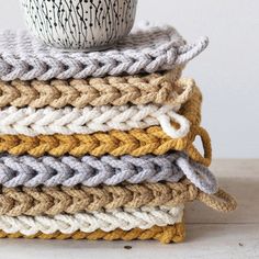 a stack of knitted blankets with a coffee cup on top