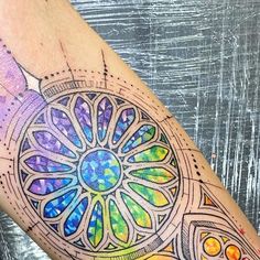 a colorful tattoo on the leg of a woman's arm with an intricate design