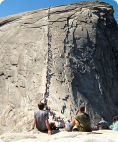 several people are sitting on the side of a mountain