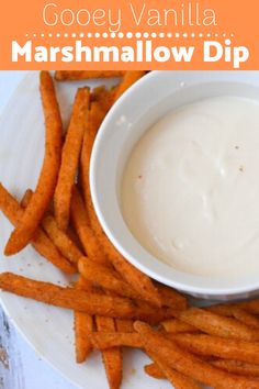 a white plate topped with french fries covered in ranch dressing next to a bowl of dip